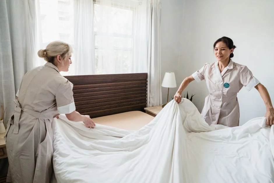 a-woman-in-a-green-shirt-and-black-gloves-vacuuming-a-gray-ottoman-5txz228u4eo