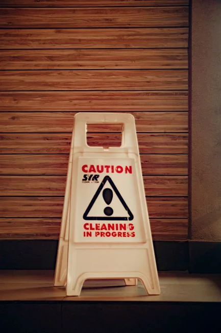 Person using spray bottle and cloth for cleaning a kitchen shelf, ensuring hygiene and cleanliness.